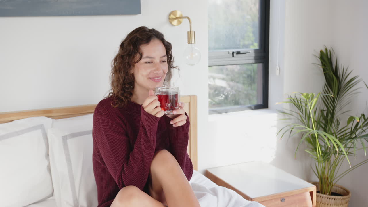 Relaxing in bed, woman drinking herbal tea and enjoying morning routine