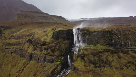 Drone-flight-towards-wind-blown-waterfall-in-Iceland