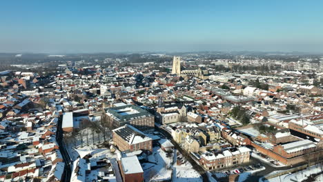 aerial flying over tongeren city in sunny winter day, roofs with snow, belgium