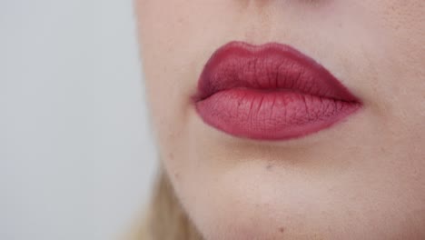 primer plano extremo de los labios rojos de una mujer hermosa mientras fuma un cigarrillo y sopla humo