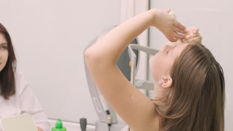 la joven instila gotas para los ojos antes de instalar lentes de contacto nocturnas en el consultorio de un oftalmólogo.