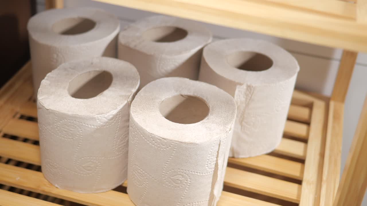 Multiple rolls of toilet paper on a wooden shelf