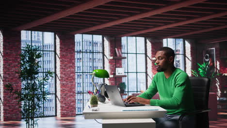 vertical video focused male freelancer browsing web on laptop in a modern studio loft