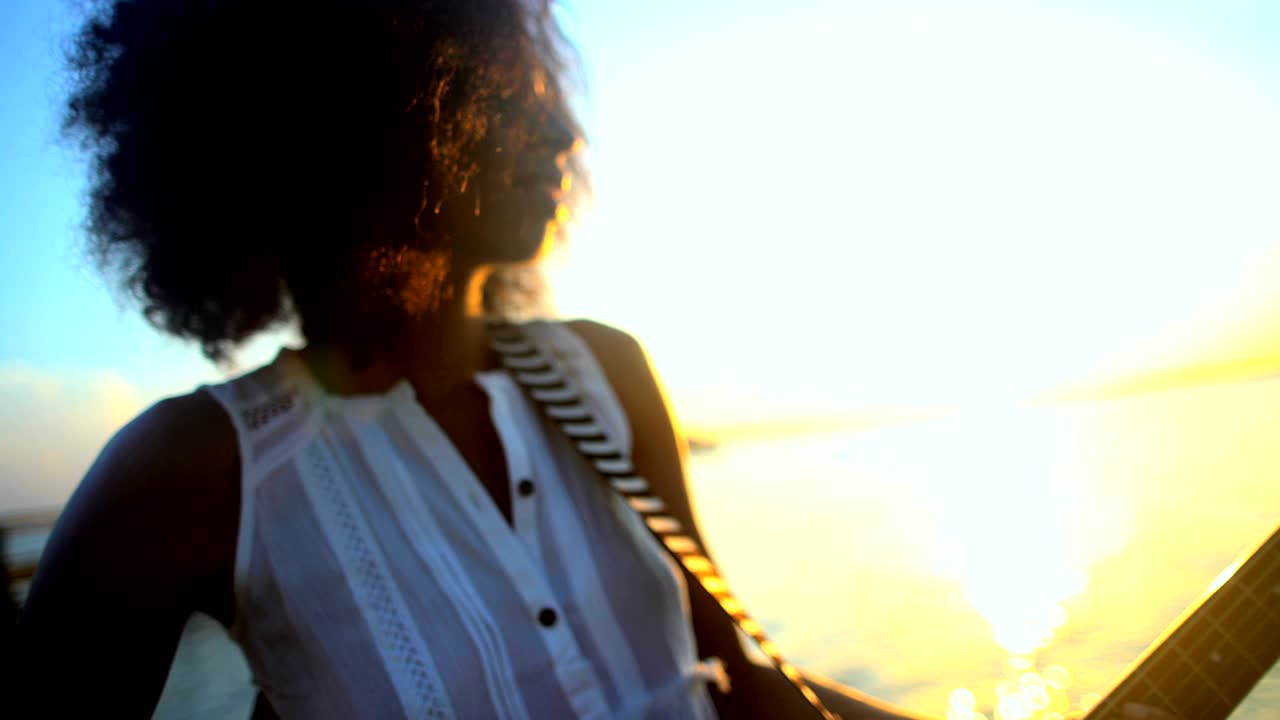 Afroamerikansk kvinde spiller guitar på strandferie