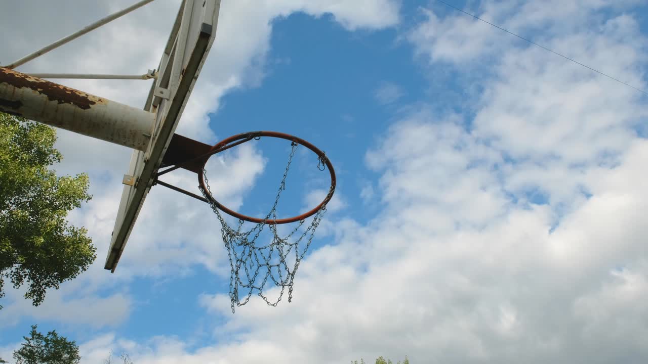 una pelota de baloncesto pasa a través de una vieja canasta de metal al aire libre. vista lateral, concepto deportivo