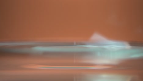 drops of water on the surface of the water on shiny orange background close up