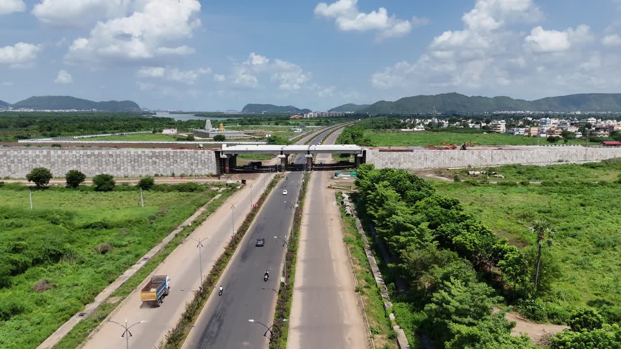 Drone shot of a calm countryside road running through green farmland in Amaravathi.