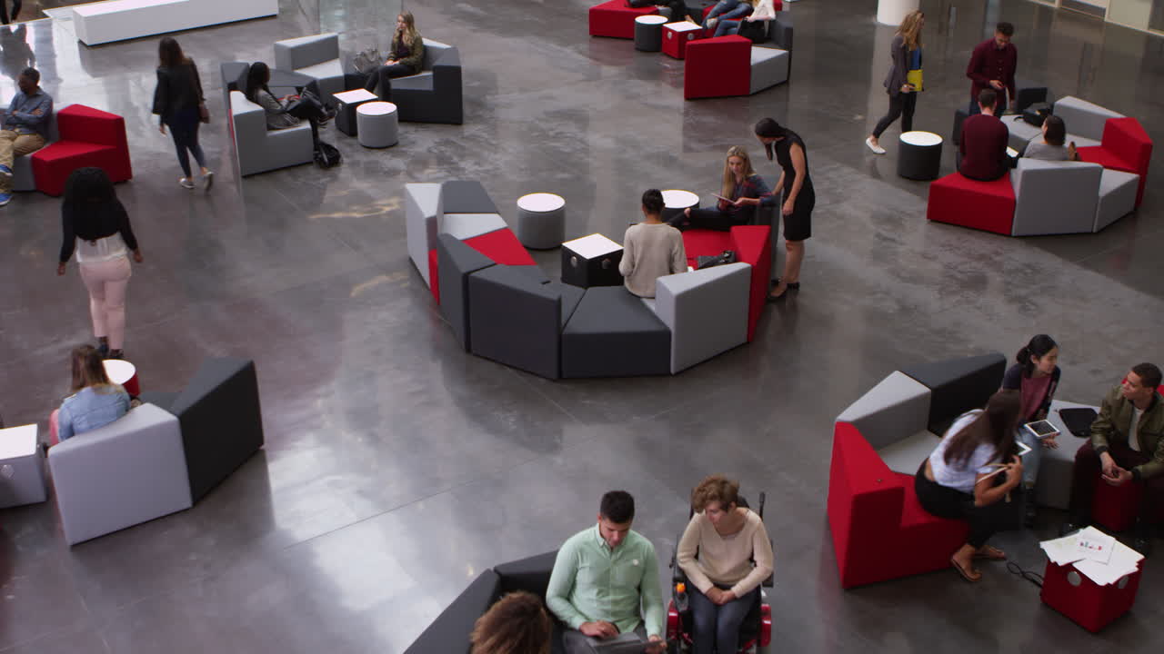 Elevated pan shot of students in busy university lobby area, shot on R3D