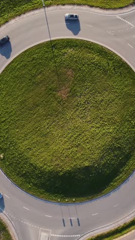 traffic around roundabout with green grass in middle, aerial top down vertical view