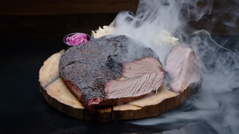 perfectly grilled pork ham on a rustic wooden plate with sides covered with a thick cloud of smoke - tilt-up medium shot