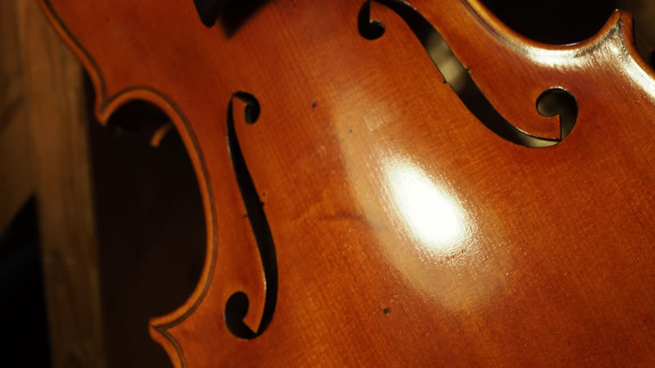 Extreme close-up of a luthier varnishing the delicate ribs and edges of a handcrafted violin, highlighting the controlled brushwork and beautiful amber Cremonese finish