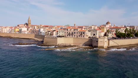 Clip-of-the-ocean-waves-crushing-on-the-rocks-and-the-medieval-castle-walls-of-the-Alghero-town-in-Sardinia,-Italy