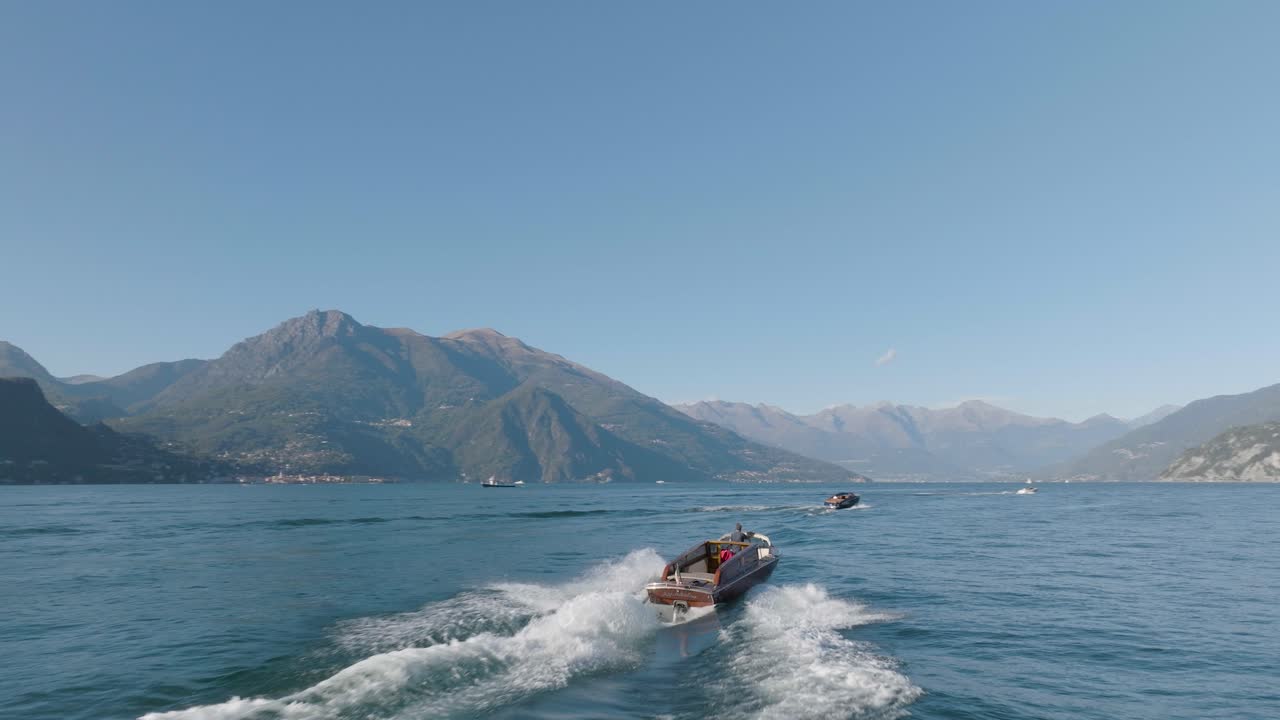 antena 4k - siguiendo de cerca detrás de un barco clásico en el lago de como, italia