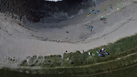 Vacacionistas-Disfrutando-De-La-Playa-De-Arena-Gris-Y-Agua-Turquesa-En-Verano,-Vista-Aérea