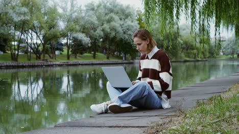 woman working on laptop in a park by the river