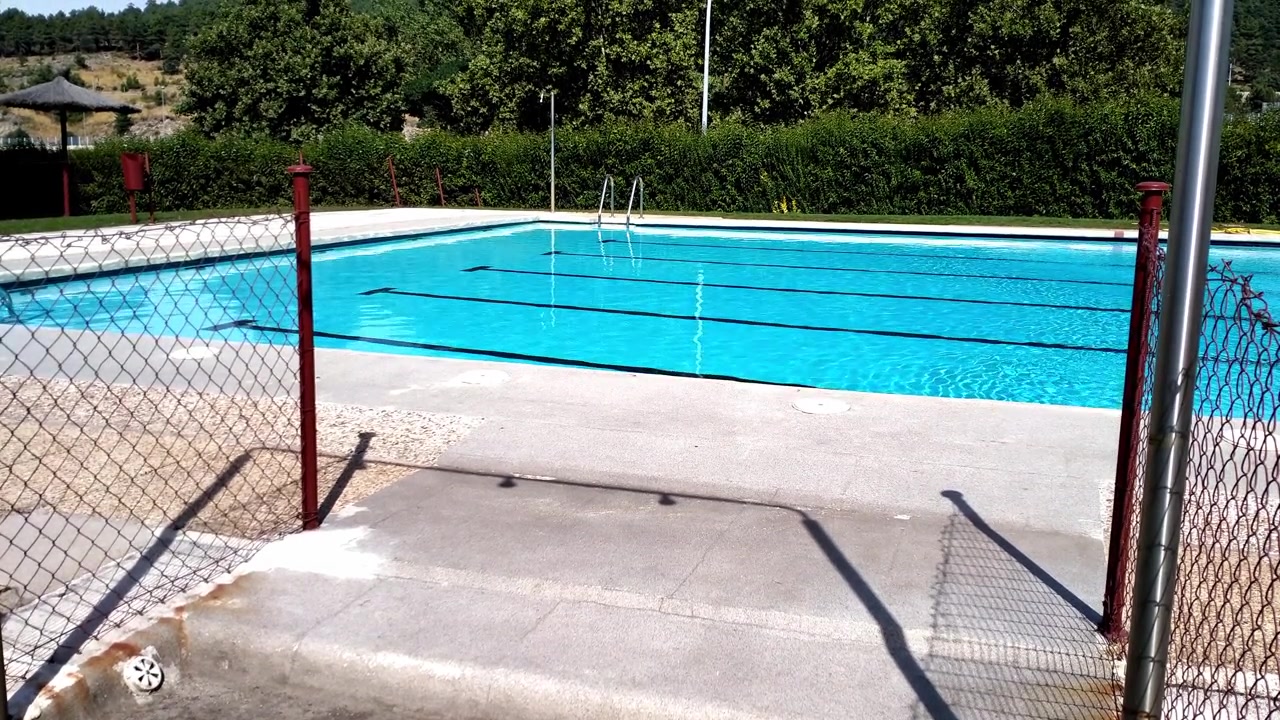 Vidvinkelbillede af tom udendørs swimmingpool med klart vand på en solrig dag