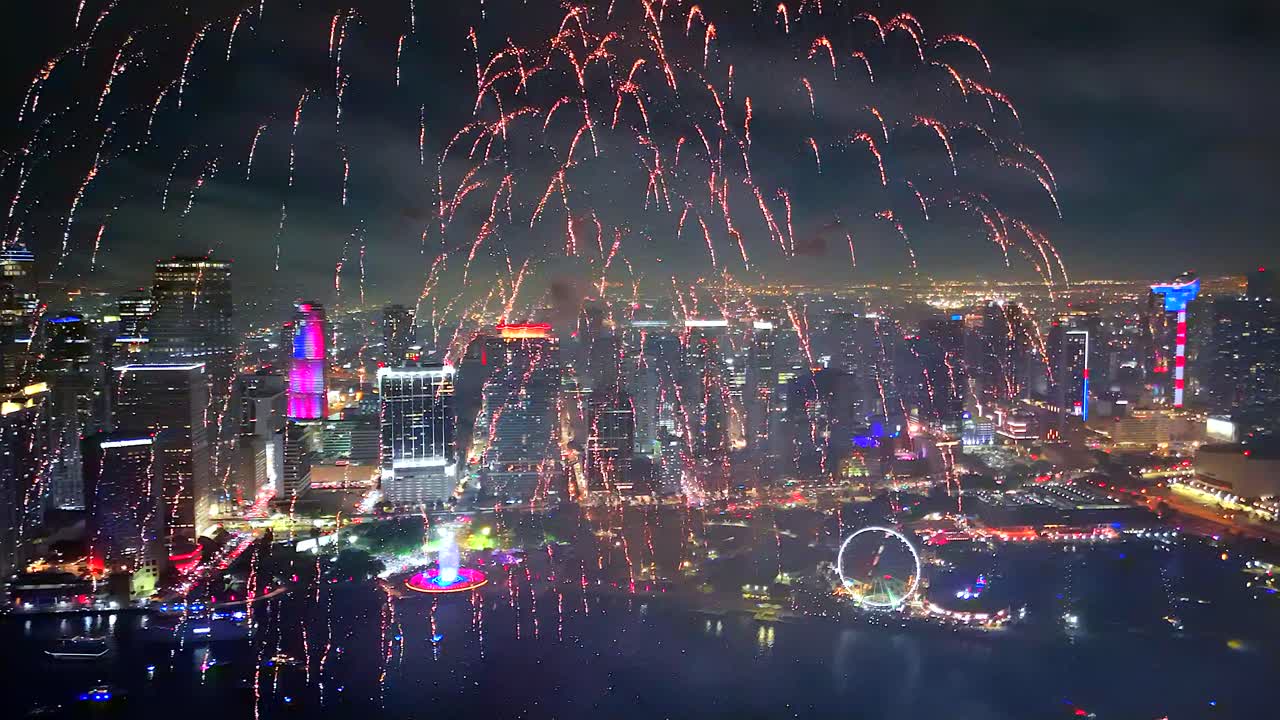 his drone-shot firework show lights up the sky with massive bursts, trailing smoke and color across a sparkling bay full of boats