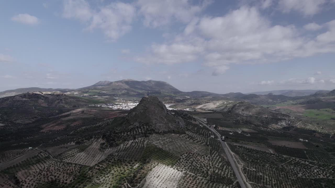 Aerial 4K footage of Olvera, Spain, captured with a DJI drone at 30fps. A cinematic view of open meadows with a stunning castle atop the mountain in the background.