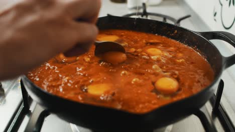 el chef agrega la yema de huevo a la mezcla de puré de verduras dentro de una sartén negra profunda
