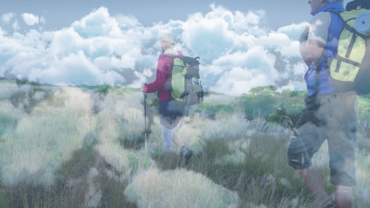 woman hiker using trekking poles and man hiker walking grassy meadow, with travel data overlay