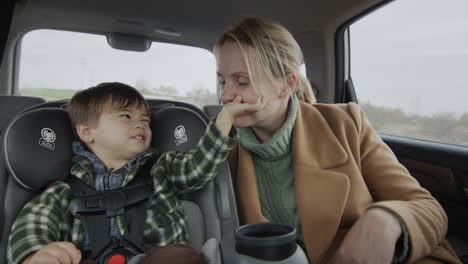 Madre-E-Hijo-Conduciendo-En-El-Asiento-Trasero-Del-Auto