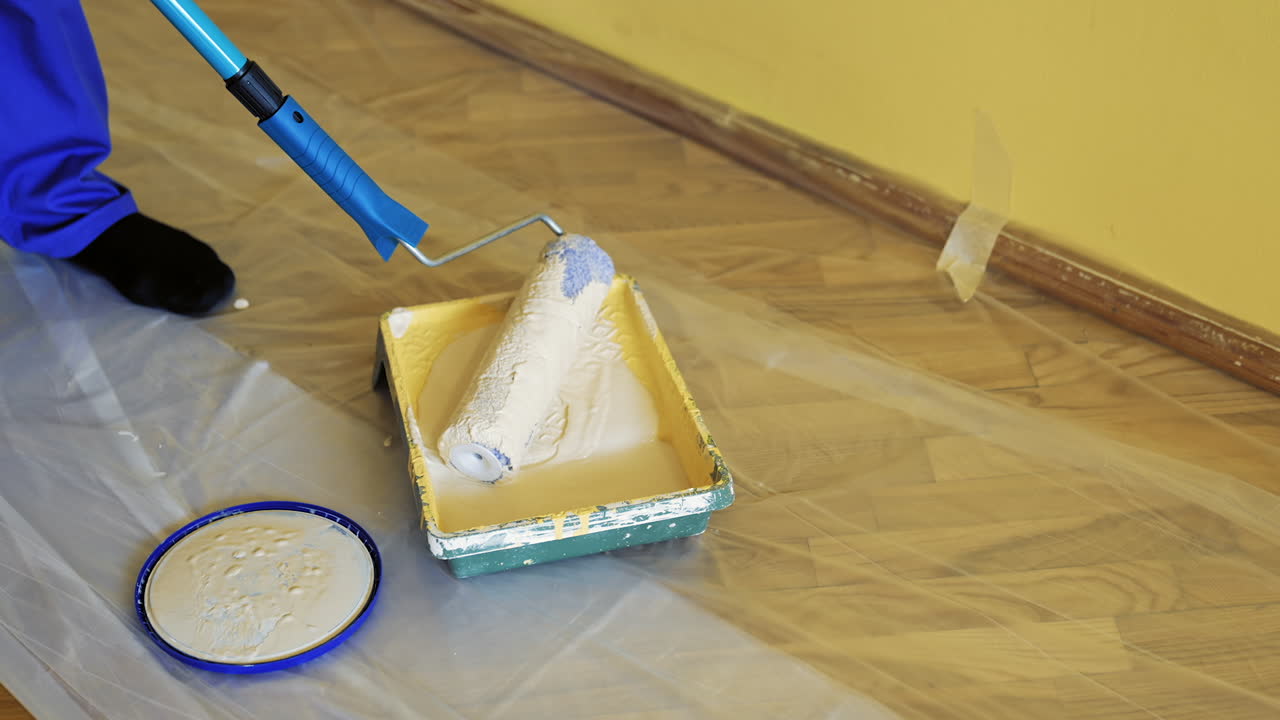 Painter put down roller into paint tray to renovate painting walls. Apartment decorating and home. Construction while renovating and improving. Close-up.