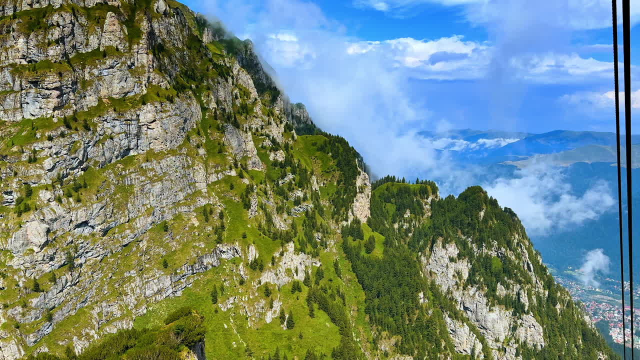 Mountain cliffs of the Carpathians with mist and valley view. High cliffs with green slopes and forest in the Carpathians with clouds over the valley