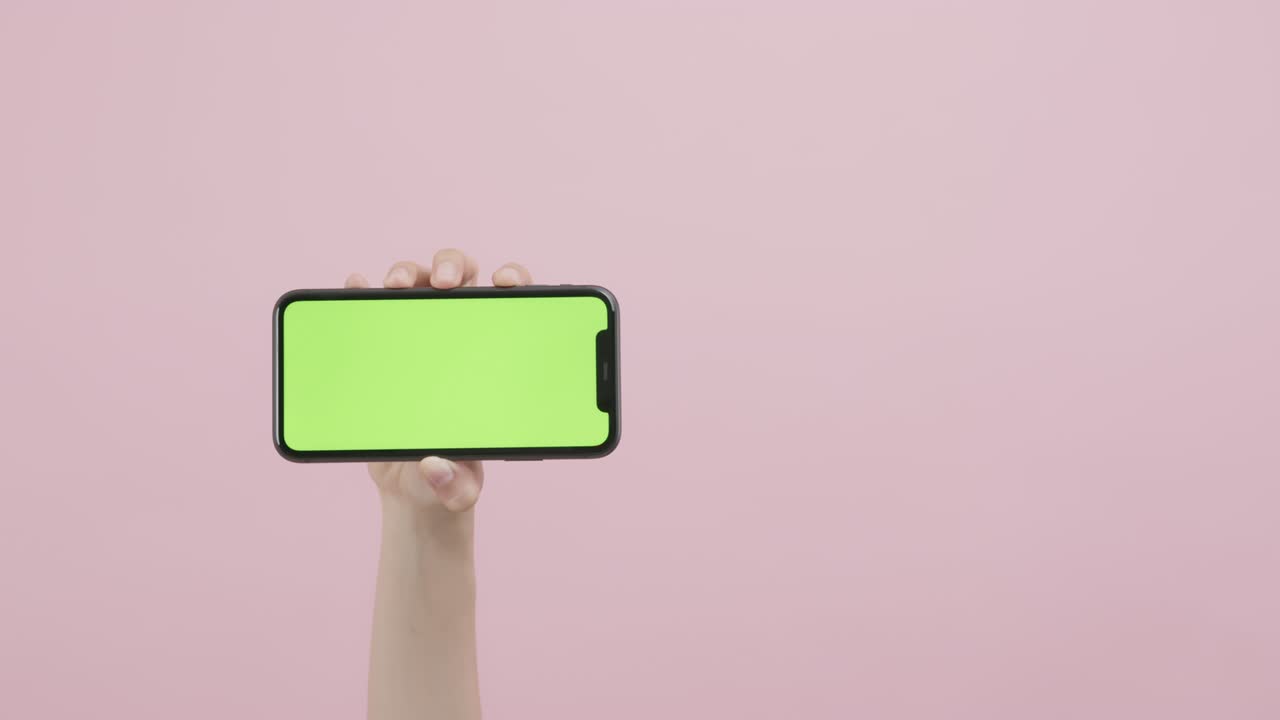 mano sosteniendo un teléfono inteligente con pantalla de tecla de croma y mostrando en el fondo rosa.