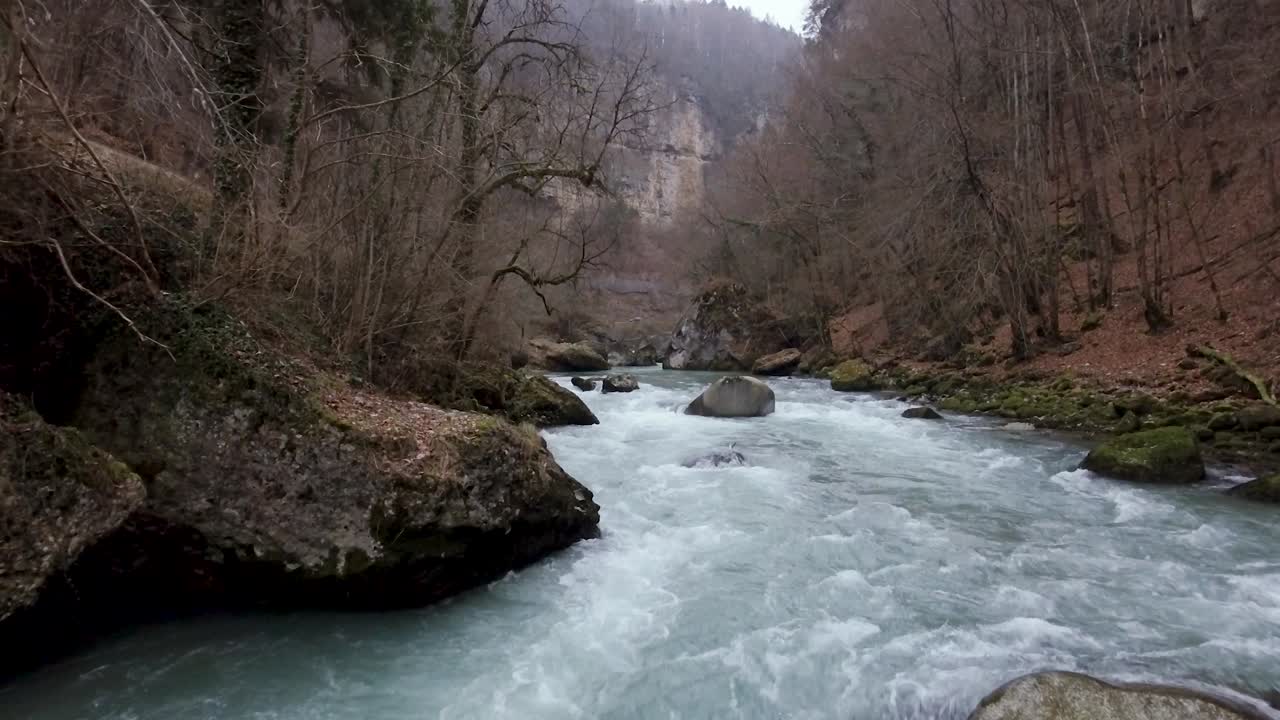 Un drone sorvola una gola di fiume in una giornata invernale nebbiosa e cupa.