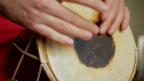 close up of hands of a man playing a drum.