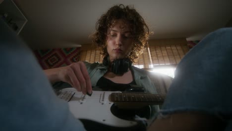 woman playing electric guitar at home