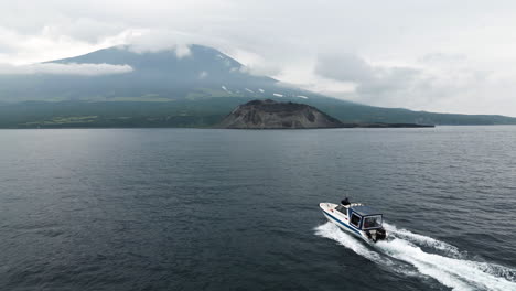 el barco navega hacia una isla salvaje con un volcán