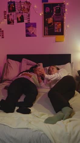 two friends laughing in bed together