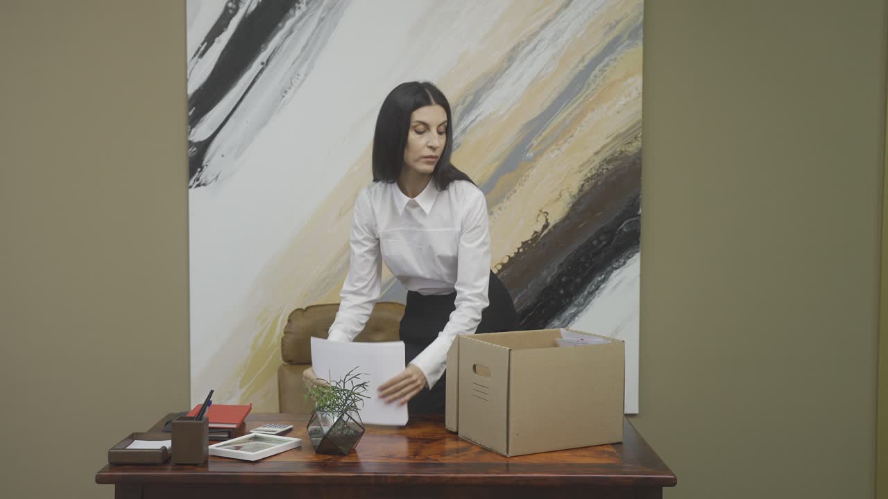 серьезная сотрудница собирает офисные вещи и проверяет свой ежедневник после увольнения