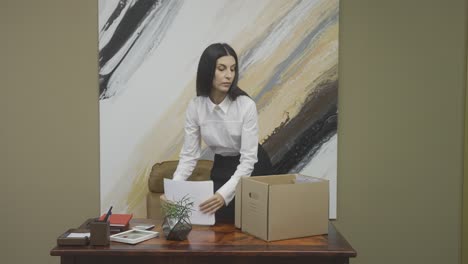 serious female employee packing office stuff and checking her agenda after resignation