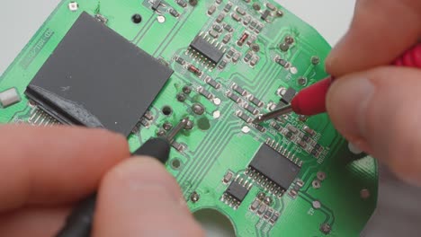 man diagnosing a faulty circuit board with a multimeter