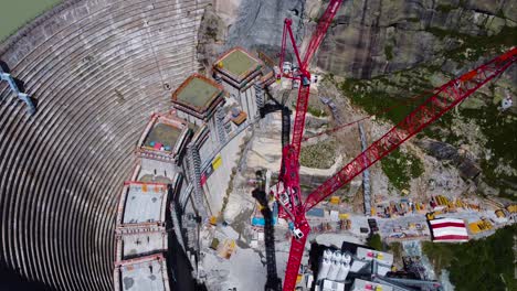 Aerial-drone-top-down-shot-over-a-dam-under-construction-in-Grimsel-Pass,-Swiss-Mountain,-Switzerland-on-a-sunny-day