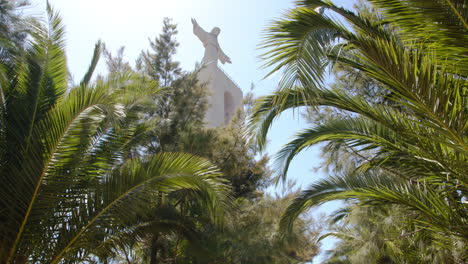 monumento a cristo rei entre las palmeras bajo un cielo azul en portugal