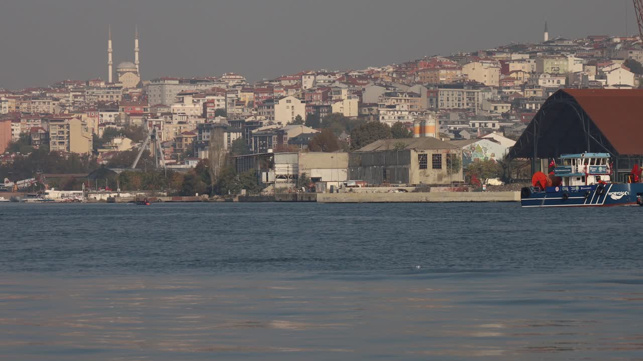 City skyline and harbor across calm sea during daylight with distant buildings