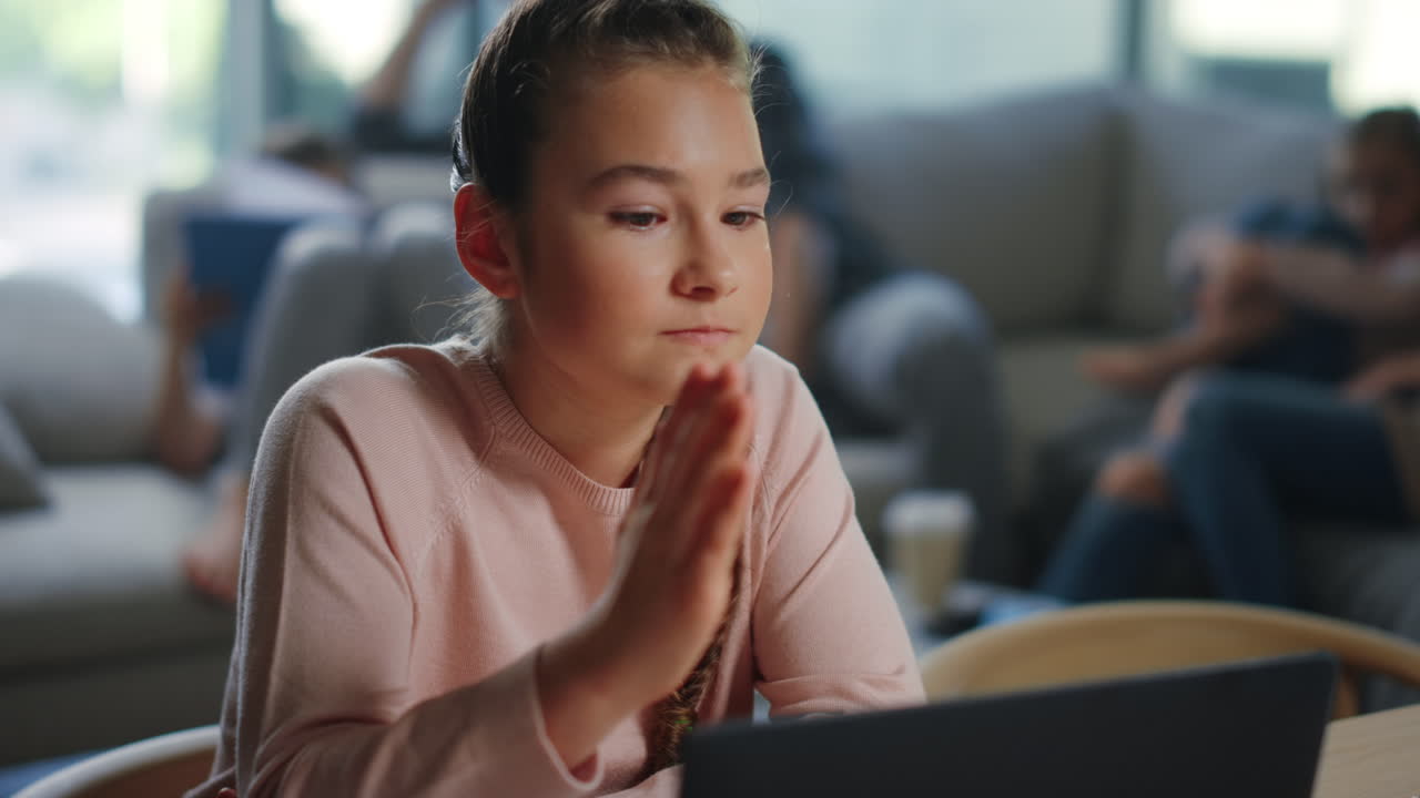 Scolara che alza la mano durante una lezione a distanza. Ragazza seria che segue una lezione online.