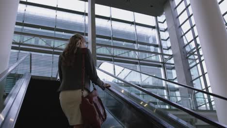 businesswoman moving upstairs on escalator in the office 4k