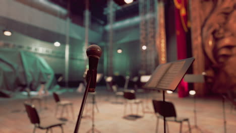 a microphone on a stage with empty chairs and music stands