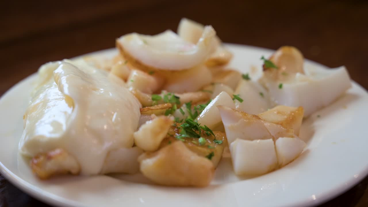 갈리시아 타베르나에서 긴 오징어, 올리브 오일과 신선한 파슬리로 우아하게 여, 단순함과 맛의 맛있는 혼합을 보여줍니다.