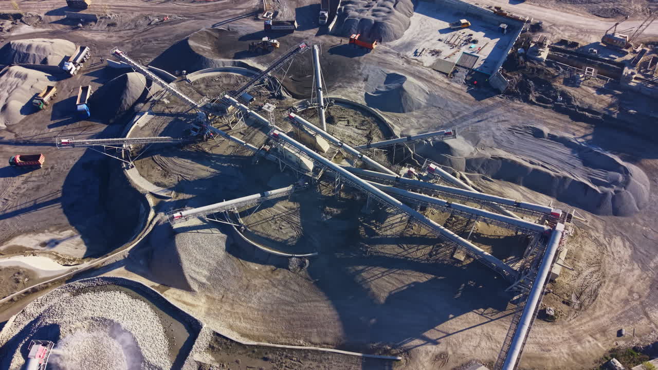 Construction site at dawn with heavy machinery and stockpiles creating a bustling atmosphere