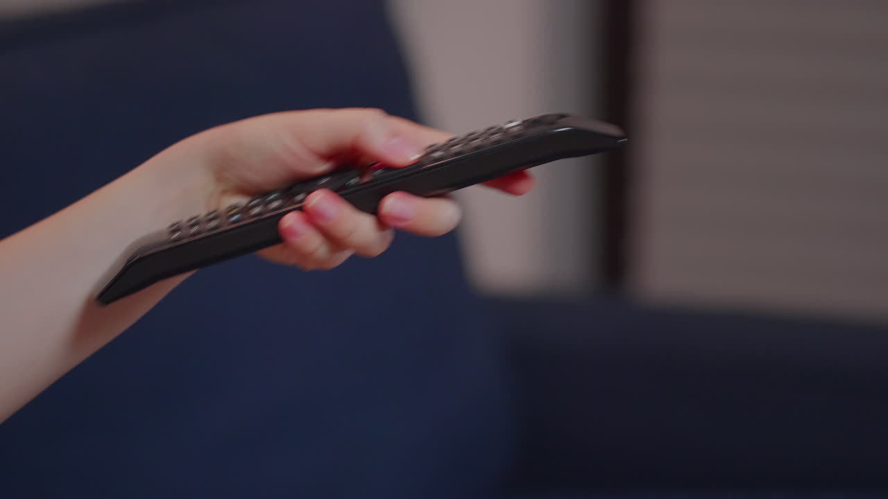 Close up of caucasian hand with TV remote switching channels