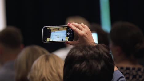 person recording a presentation with a smartphone