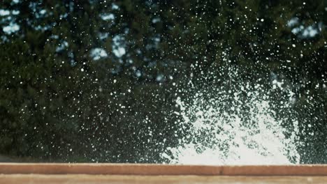 boy in goggles leaps into pool as water splashes in air, view from side