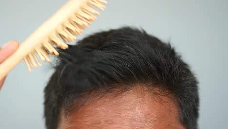 hombre cepillándose el cabello con un pincel de madera