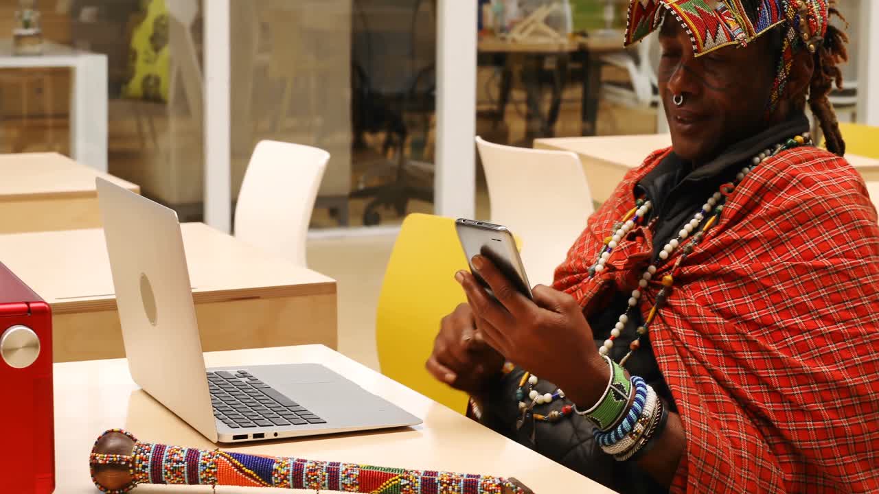 Homme tribal utilisant un téléphone portable et un ordinateur portable 4K
