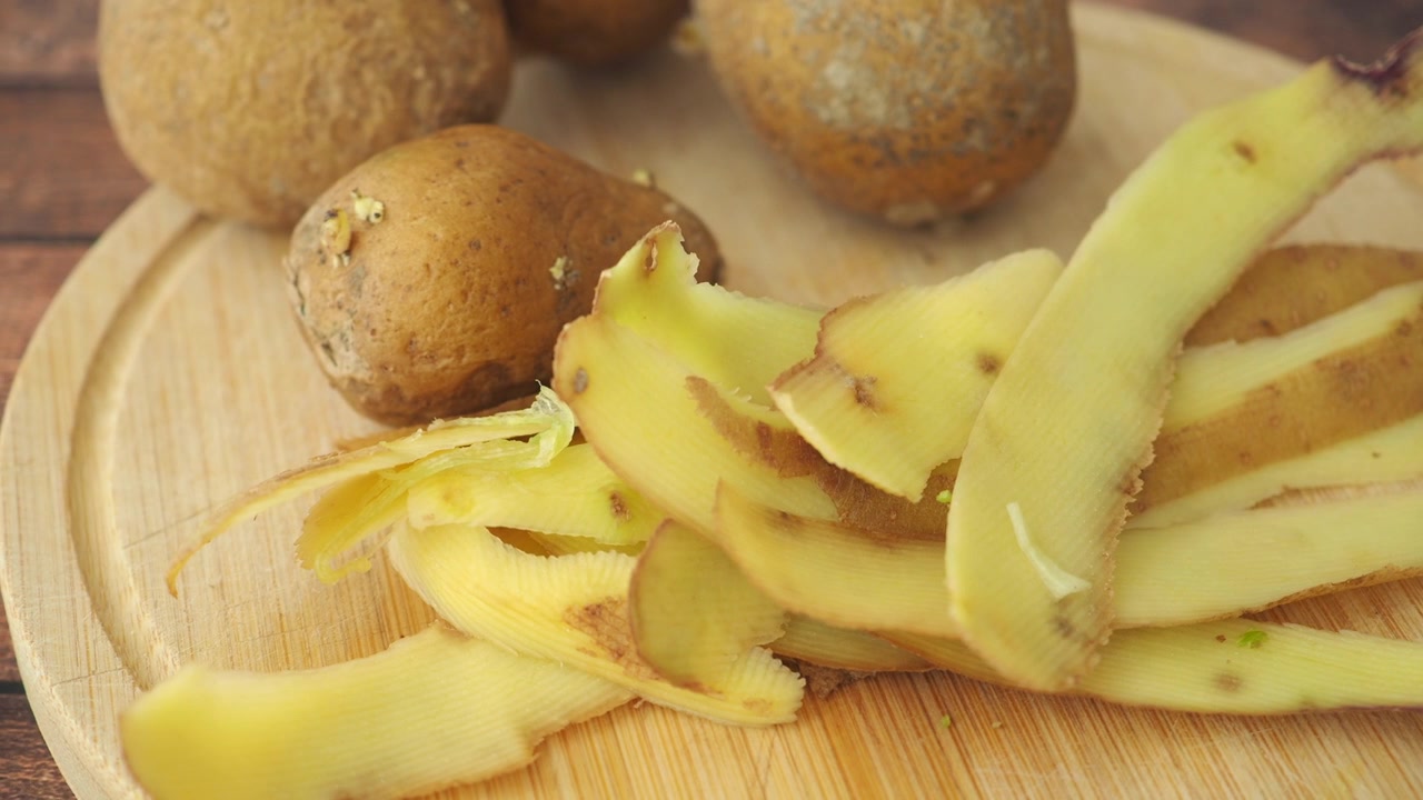 Bucce di patate fresche su un tagliere di legno